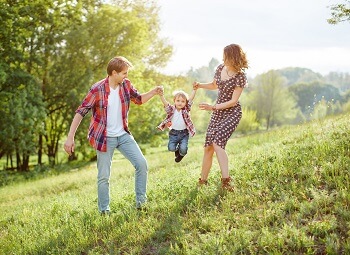 Family of three, man and woman playing with their son outside