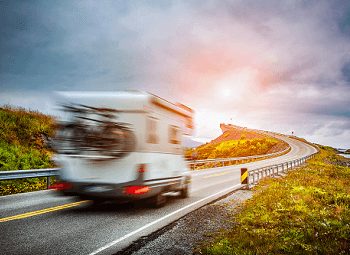 Blurred shot of an RV with bikes on a rack on the back driving down a highway